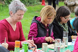 Das Bild zeigt Frauen, die an einem Tisch sitzen und Wildkräuter zubereiten.