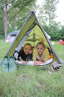Das Bild zeigt zwei Mädchen, die bei den Kanu-Abenteuer-Tagen für Mädchen liegend aus einem Zwei-Personen-Zelt schauen.