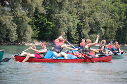 Das Bild zeigt mehrere vollbeladene Kanus mit Paddlern auf dem Wasser.