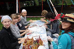 Das Bild zeigt sieben Jugendliche, die an einem Tisch sitzen und mit Speckstein arbeiten.